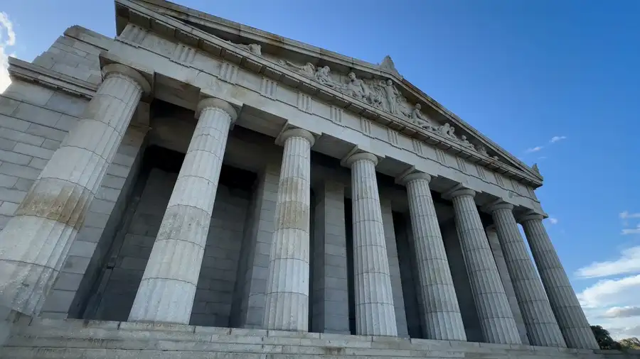 Low-angle view of a stone building with tall fluted columns under a blue sky